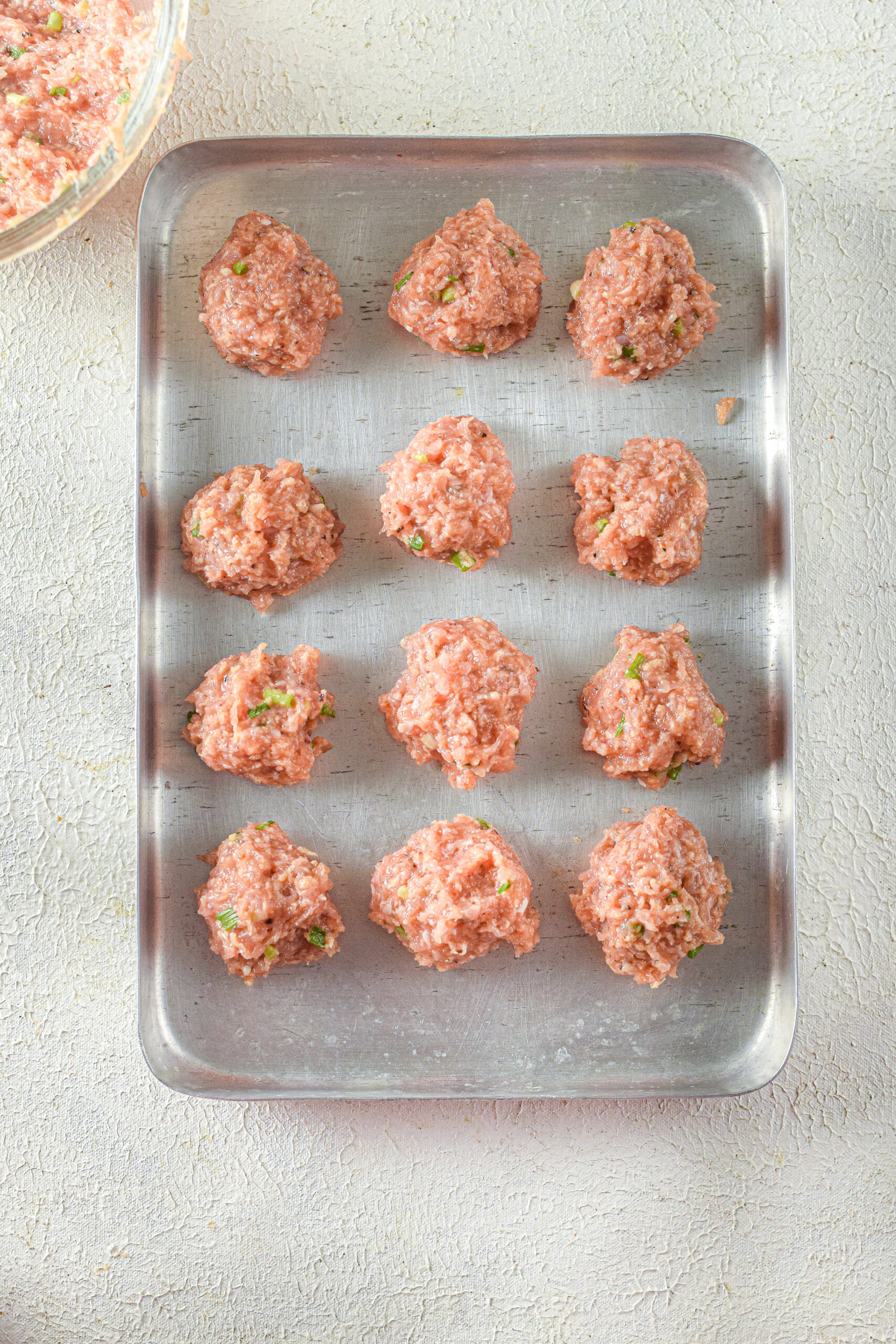 uncooked meatballs on a pan.
