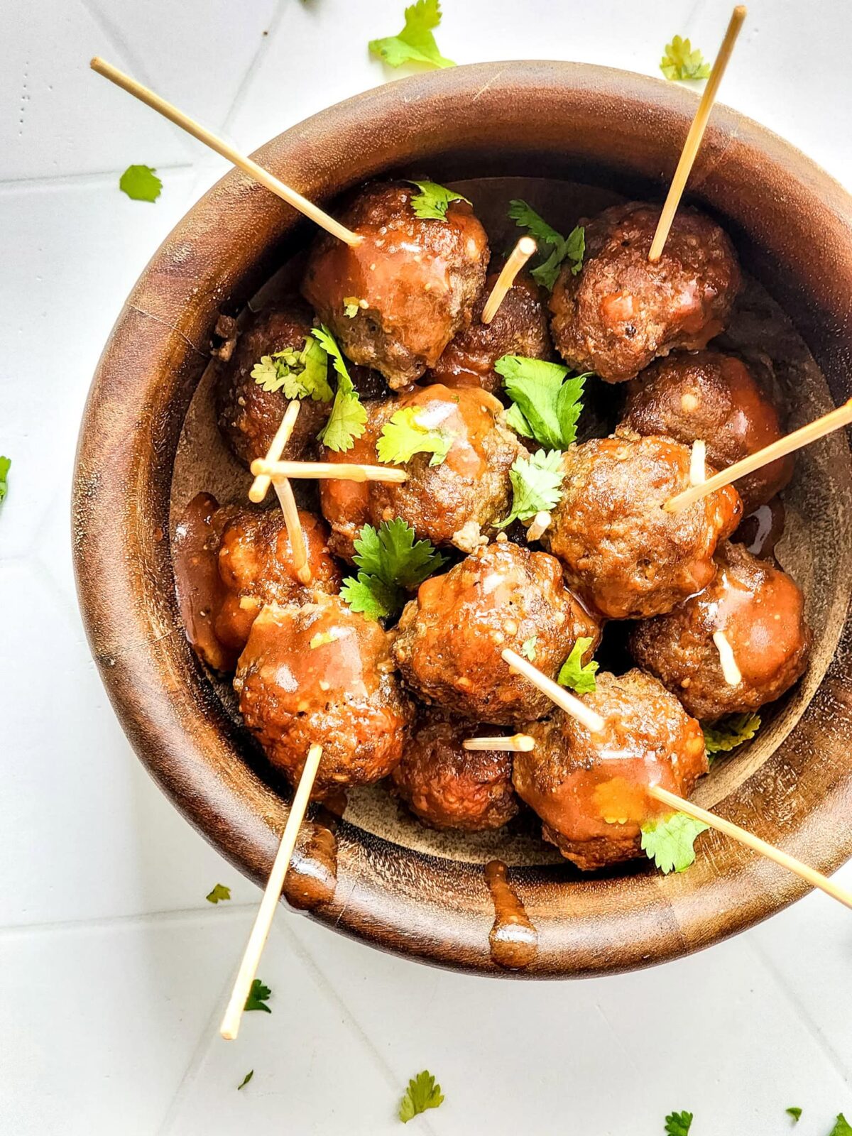 Meatballs with toothpicks in a brown bowl.