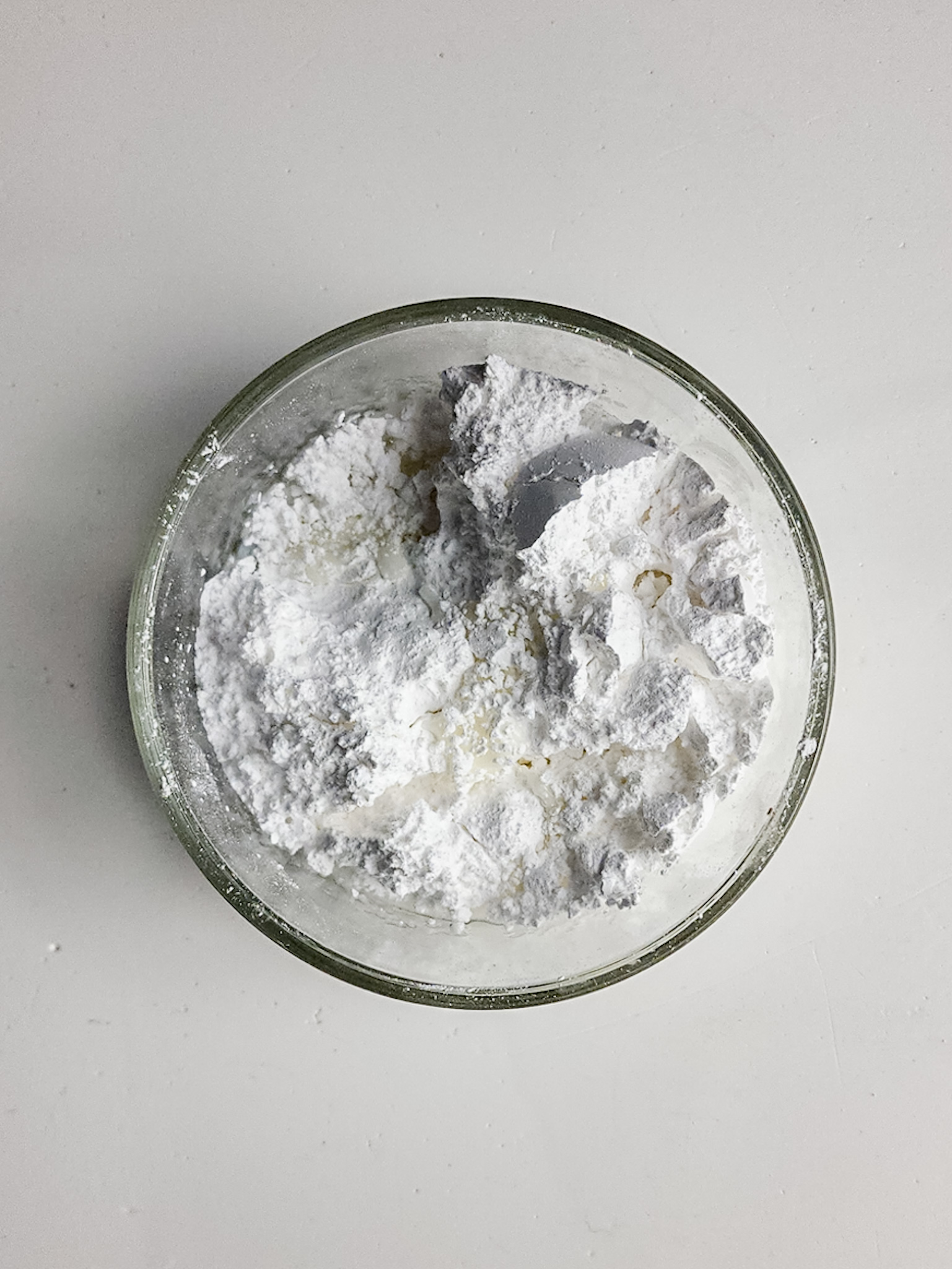 Powdered sugar, almond extract and almond milk in a glass bowl.