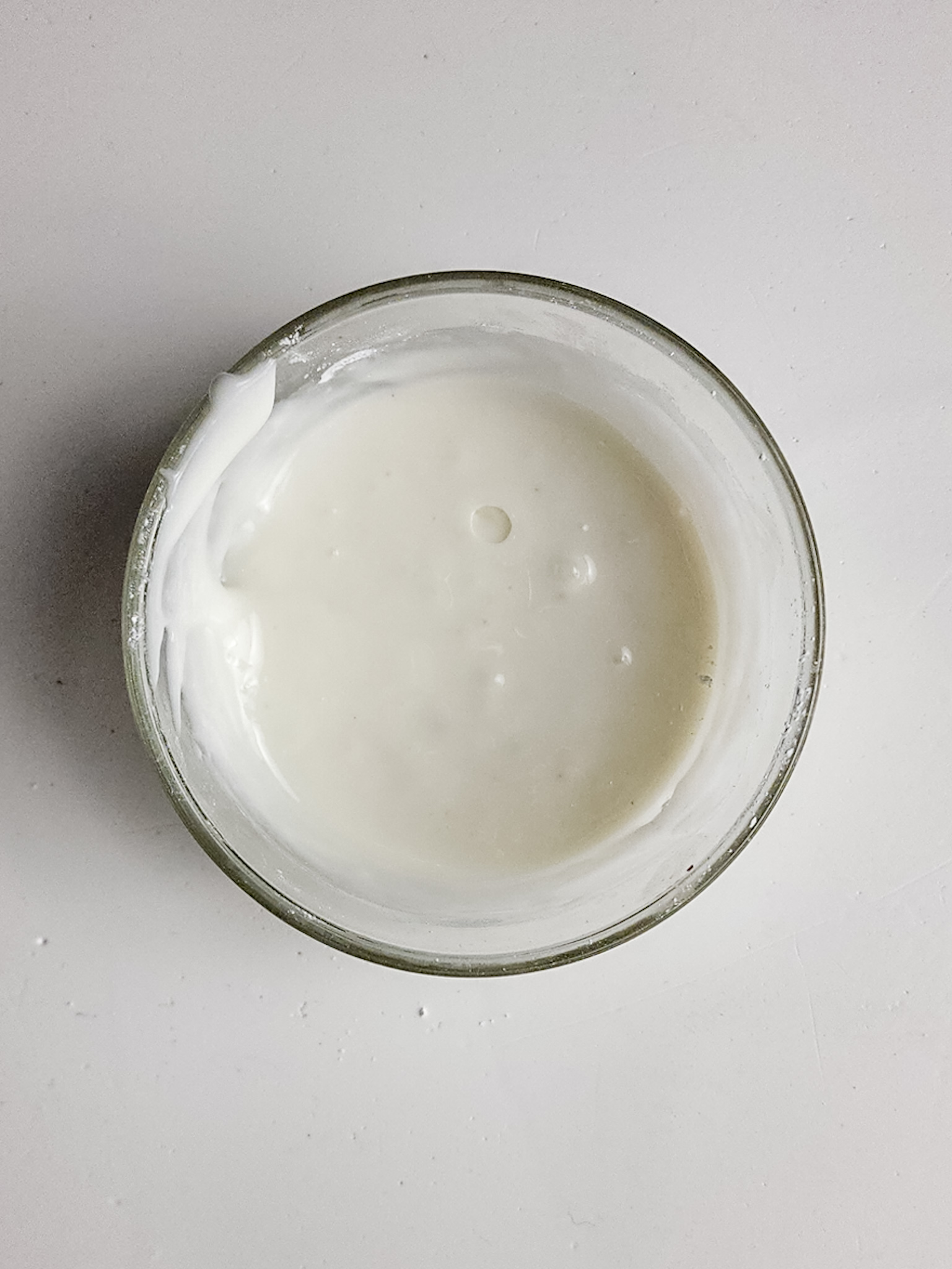 Powdered sugar, almond extract and almond milk in a glass bowl mixed together.