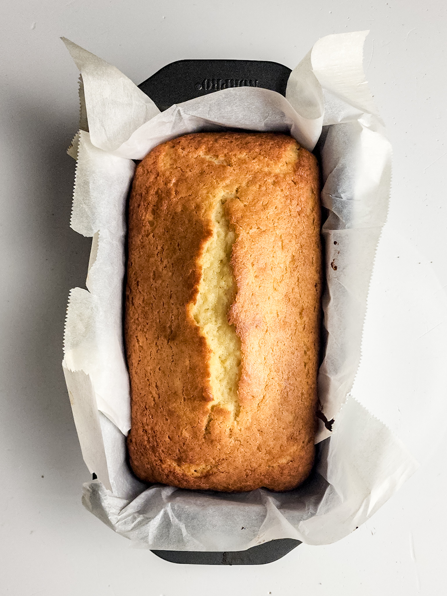 Baked cake in parchment lined loaf pan.
