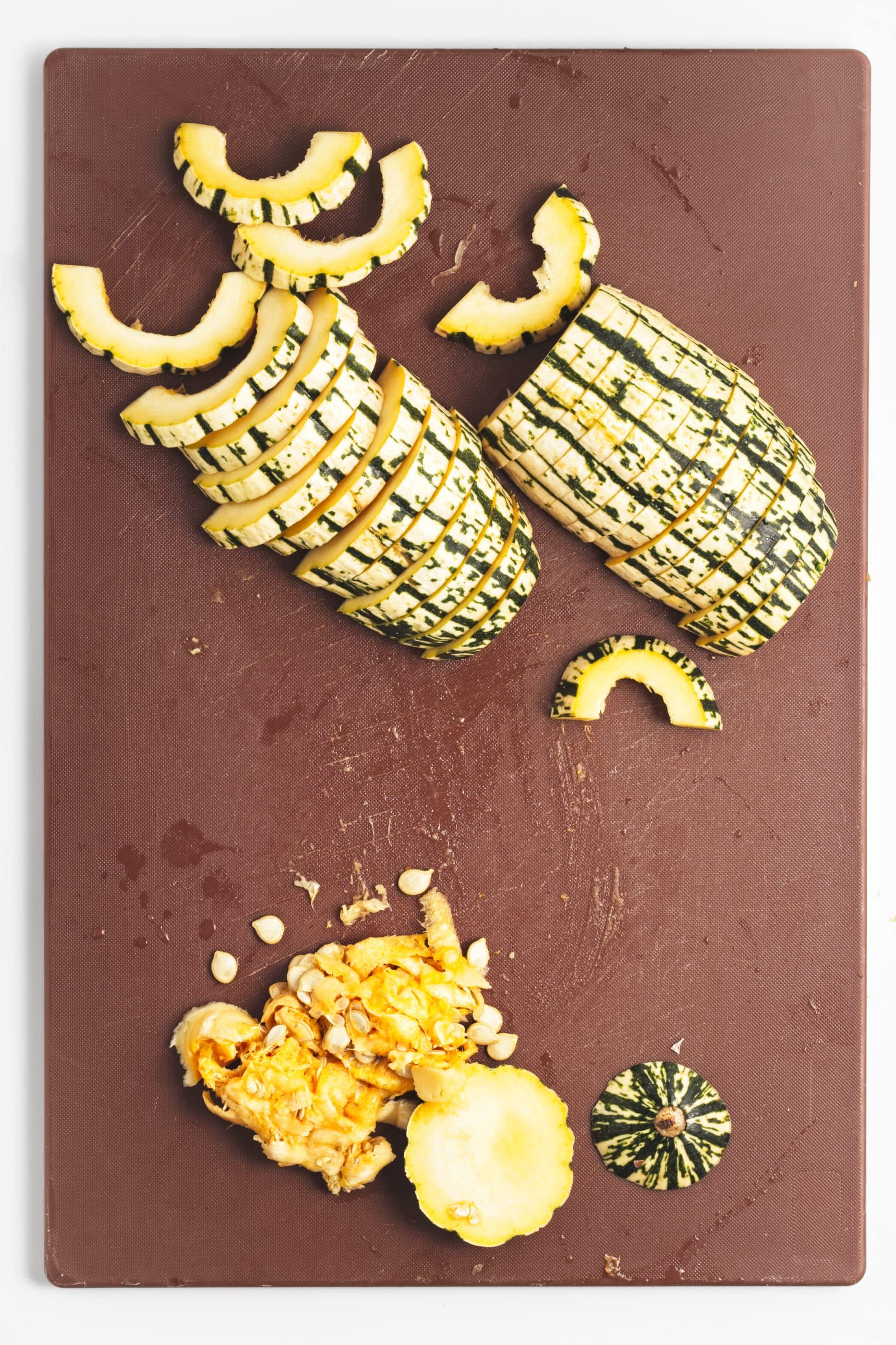 Sliced delicata squash on a cutting board.