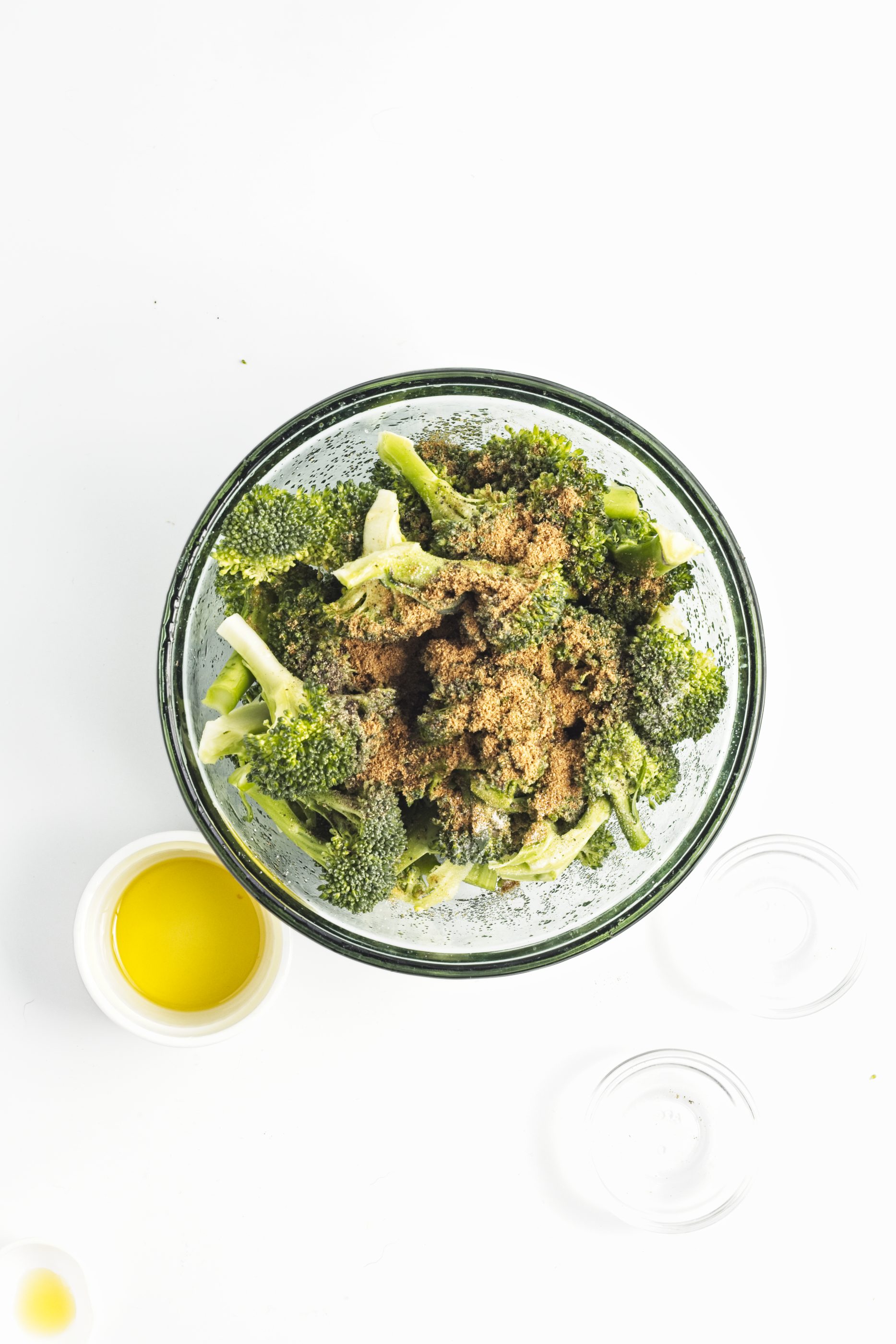 Broccoli and seasonings in a glass bowl.