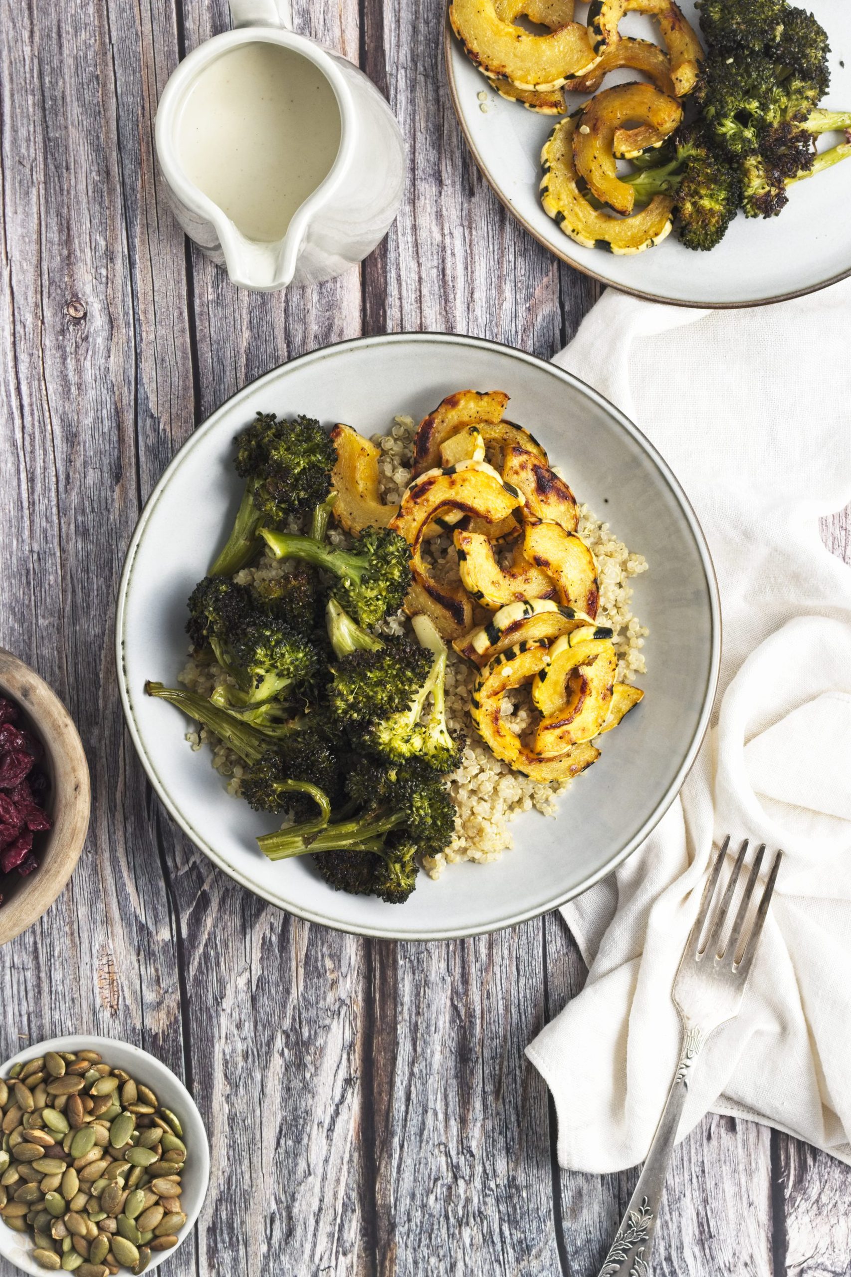 Cooked quinoa with roasted broccoli and squash on top in a bowl.