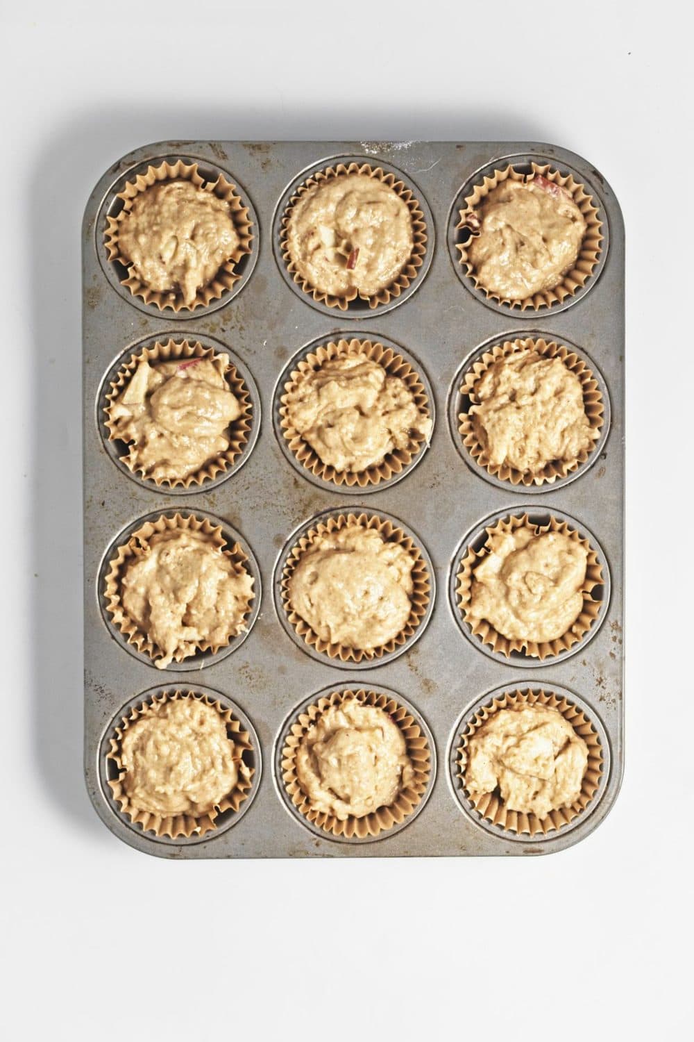 Apple crumb muffin batter in lined muffin tins.