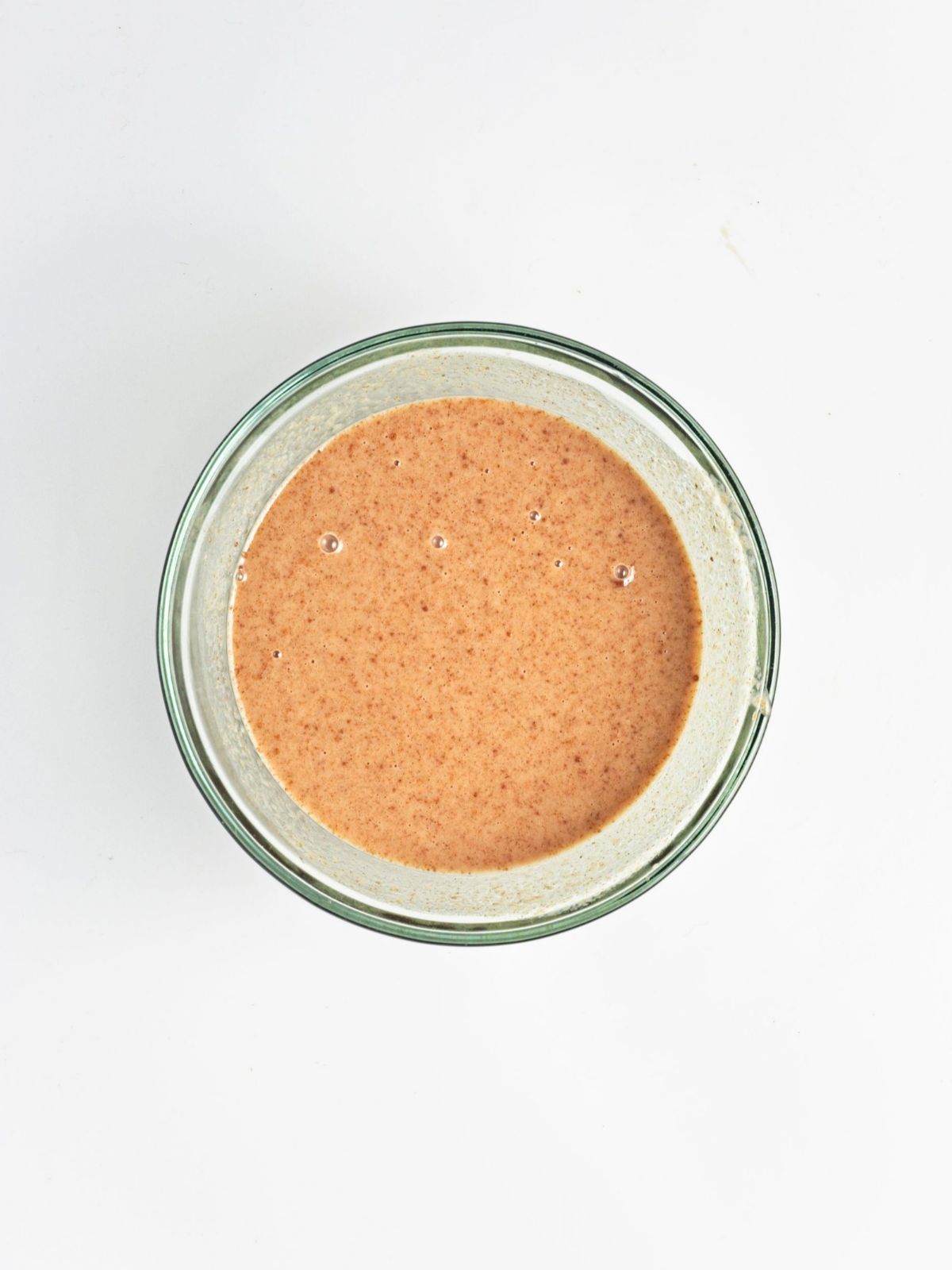 Smooth cinnamon-spiced wet mixture in a glass bowl for gluten-free baked apple protein oatmeal, ready for the oats and other dry ingredients.