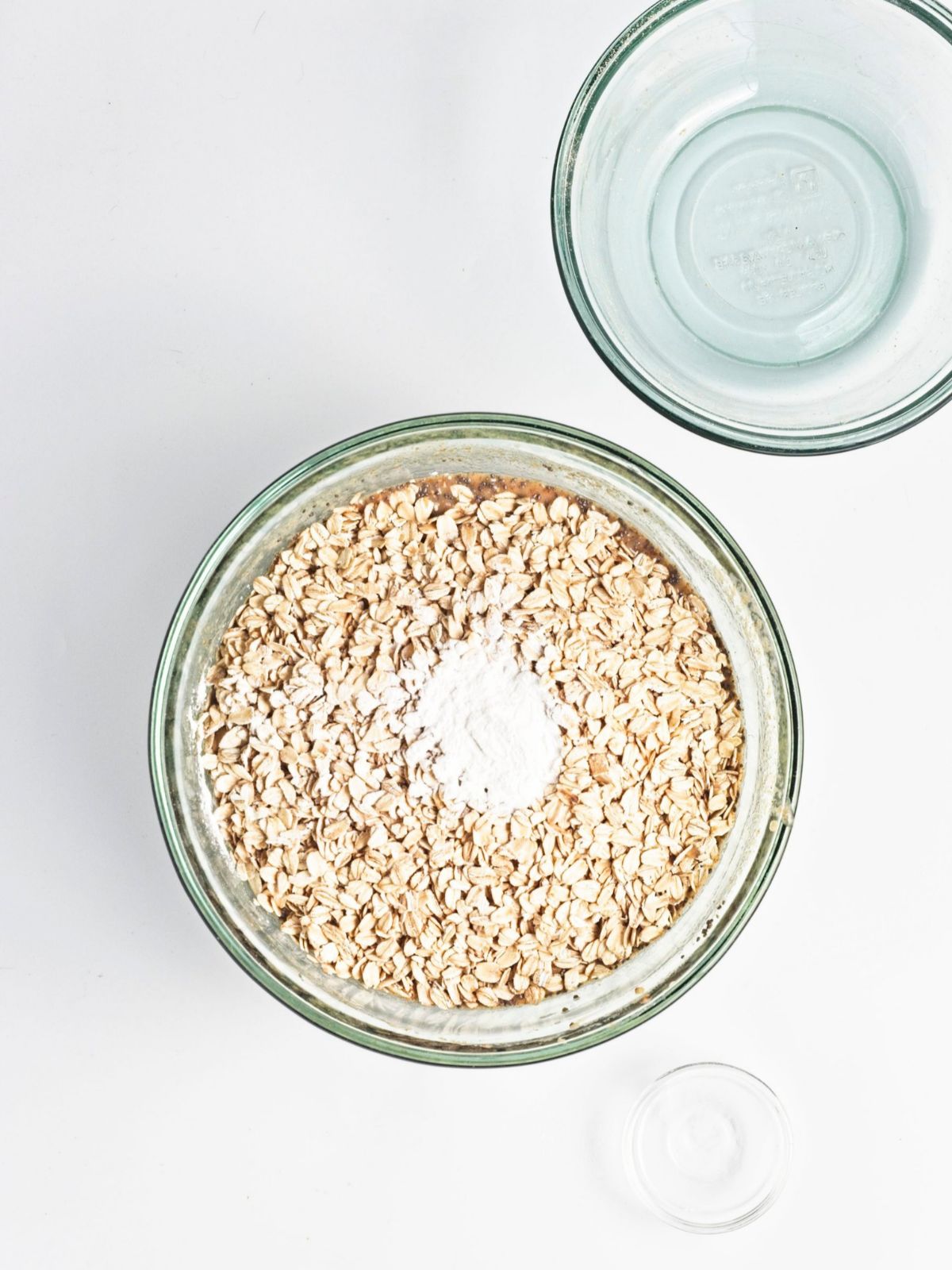 Oats, protein powder and baking powder with chia seed batter mixed into a glass bowl for vegan baked apple protein oatmeal, ready for the remaining ingredients before baking.