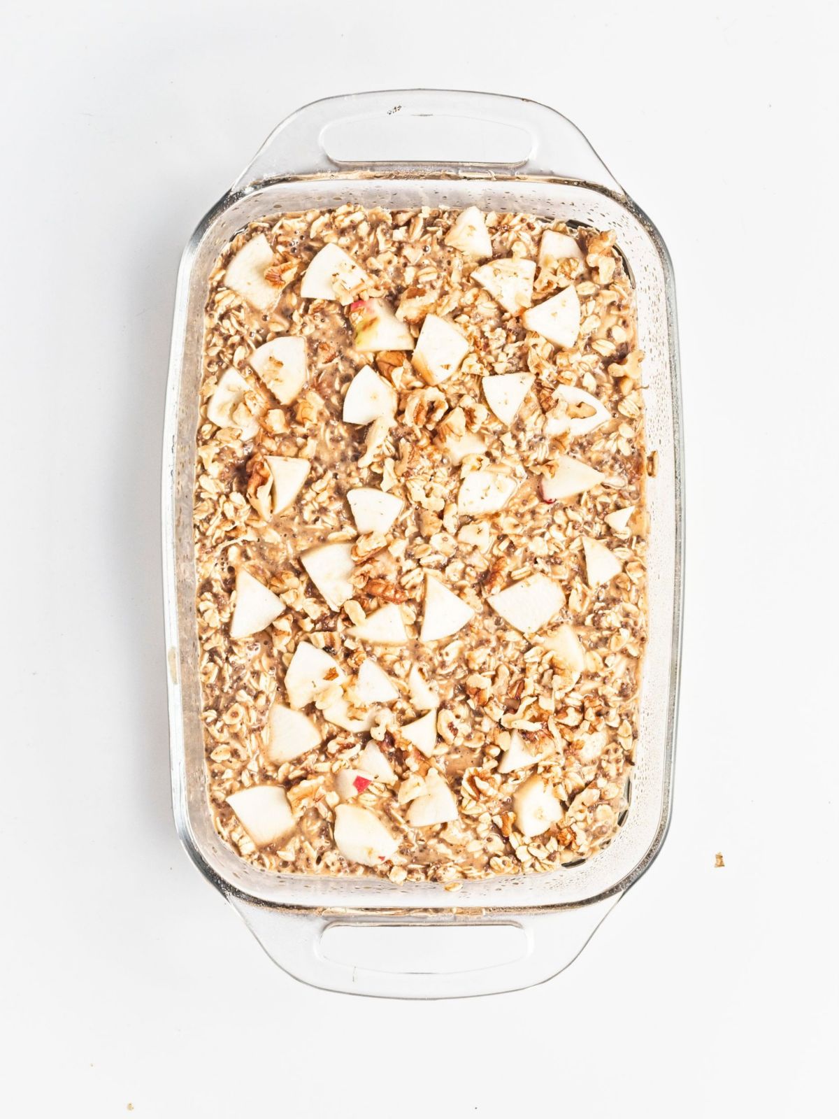 Overhead image of apple protein oatmeal with slice apples on top in a baking dish.