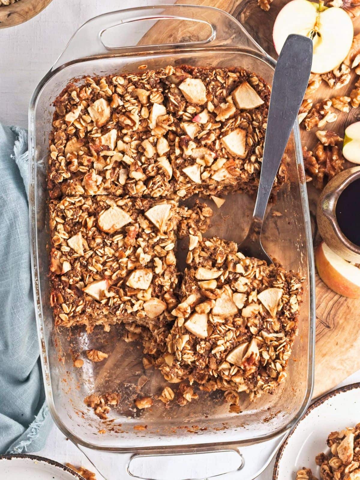 Overhead image of healthy baked oatmeal with apples in a glass baking dish, filled with rolled oats, chopped apples, walnuts, and warm cinnamon. 